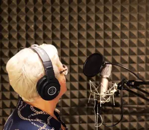 White haired woman at a microphone